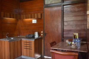 eine Küche mit Holzwänden, einem Tisch und einem Waschbecken in der Unterkunft Citra Cikopo Hotel & Family Cottages in Puncak