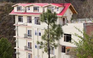 Eden Hotel and Resort في شيملا: مبنى ابيض كبير بسقف احمر