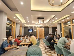 Eden Hotel and Resort في شيملا: مجموعة من الناس يجلسون على الطاولات في المطعم