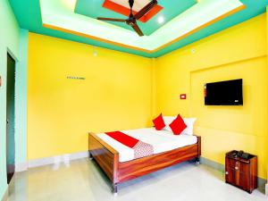 a bedroom with a bed with yellow walls and a flat screen tv at Dreams Inn in Kolkata