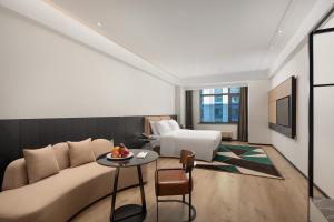 um quarto de hotel com uma cama, um sofá e uma mesa em Paradiso Jiamusi em Jiamusi