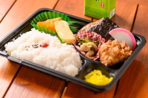 a tray of sushi and rice on a wooden table at Uwajima Oriental Hotel in Uwajima