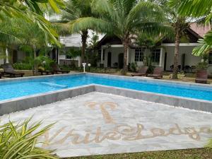 een zwembad met een bord dat nirvana leest bij White Lodge in Pantai Cenang