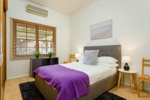 um quarto com uma cama grande e um cobertor roxo em Spacious 3-Bed Mid Century Home Near CBD em Sydney