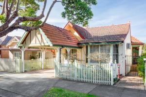 a yellow house with a white fence at Spacious 3-Bed Mid Century Home Near CBD in Sydney