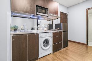 a kitchen with a washing machine and a microwave at Gratia by Kozystay - 1BR - City View - Kuningan in Jakarta