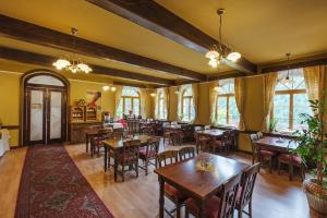 un restaurante con mesas y sillas de madera y ventanas en Alpský Hotel, en Špindlerův Mlýn