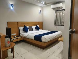 een slaapkamer met een bed met blauwe en witte kussens bij HOTEL THE GRAND DIPAK in Junagadh