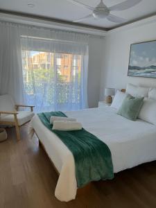 a white bedroom with a large bed and a window at Pelican Cove Apartments in Gold Coast