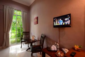 a living room with a television on the wall at White Lodge in Pantai Cenang