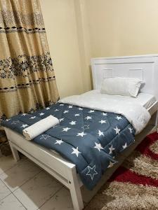 a bed with a blue blanket with white stars on it at Machakos Town Coffee Residencies in Machakos