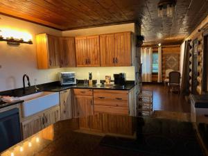 een keuken met houten kasten en zwarte aanrechtbladen bij Private Ranch Log Cabin Lakeside Escape in Shady Cove