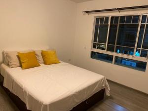 een slaapkamer met een bed met gele kussens en een raam bij Indy 2 Bangna KM 7 Cozy Townhome near Ikea Mega Bangna 15m to Airport in Bang Kew Yai