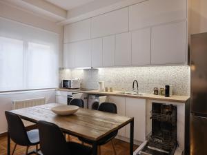 a kitchen with white cabinets and a wooden table at Sunny and Comfy 2bd Apt in Kolonaki in Athens