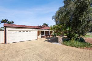 a house with a white garage and a tree at The Entertainer in Perth