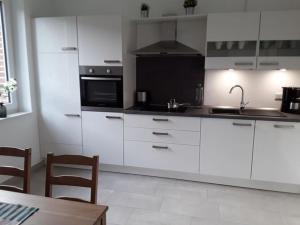 cocina con armarios blancos, fregadero y microondas en Nice holiday apartment in Ostbevern, en Ostbevern