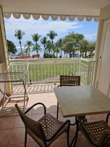 a balcony with a table and chairs and a view of the ocean at Appartements village Pierre et Vacances vue mer Guadeloupe St Anne studios ou T3 in Sainte-Anne