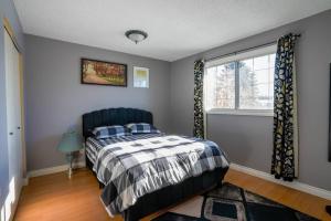 1 dormitorio con cama y ventana en Beautiful 5 BDRM Home, Fenced Yard, WiFi, Fireplace, Free Parking, Transit, Town Centre - Sleeps 12 en Edmonton