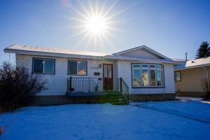 una casa blanca con el sol en el cielo en Beautiful 5 BDRM Home, Fenced Yard, WiFi, Fireplace, Free Parking, Transit, Town Centre - Sleeps 12 en Edmonton