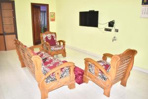 Sri Annamalaiyar Guest House في تيروفانمالي: غرفة معيشة بها ثلاثة كراسي وتلفزيون