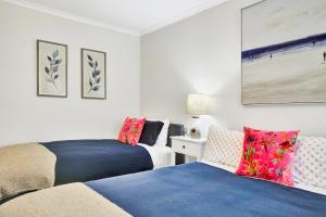 a bedroom with two beds and a table with a lamp at Henley Hideaway in Henley Beach South