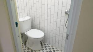 a bathroom with a toilet and a tiled floor at OYO 93785 Aero Kost Bu Lisa Syariah in Lawang