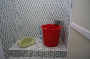 a red bucket in a bathroom with a toilet at SPOT ON 93786 Kost Alamku Syariah 