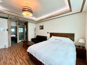 a bedroom with a bed and a chair in it at Okpo business hotel in Geoje