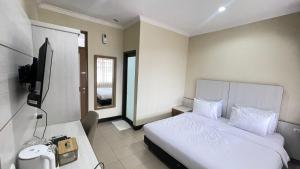 una camera d'albergo con un letto e una televisione di tekMIRA Hotel a Bandung