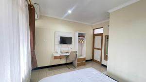 1 dormitorio con 1 cama y escritorio con TV en tekMIRA Hotel, en Bandung