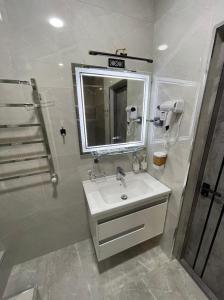 ein Bad mit einem Waschbecken, einem Spiegel und einer Dusche in der Unterkunft Art Hotel Navoiy in Navoiy