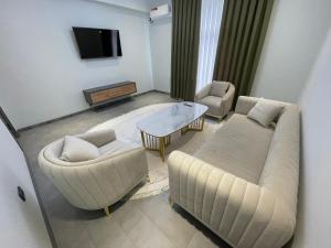 sala de estar con sofá, mesa y sillas en Art Hotel Navoiy, en Navoi