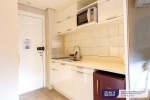 uma cozinha com armários brancos e um micro-ondas em MH 50201 - Charmoso Studio Expo CN AC/WF/GARAGEM em São Paulo