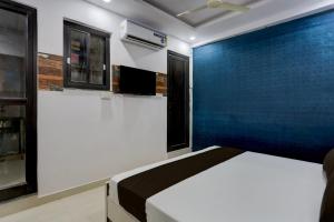 1 dormitorio con cama y pared azul en OYO Flagship Hotel OM Shree, en Kānpur