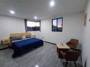 um quarto com uma cama azul, uma mesa e cadeiras em Máster Suite Departamento cerca de Isla San Marcos em Aguascalientes