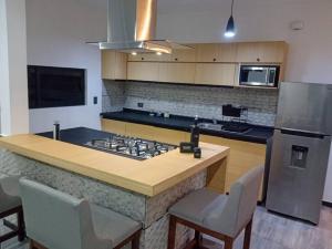 a kitchen with a stove and a counter top with chairs at Máster Suite Departamento cerca de Isla San Marcos in Aguascalientes