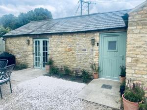 a stone shed with a green door on it at Cotswolds Cottage 5min from Soho Farmhouse in Chipping Norton