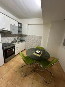 uma cozinha com uma mesa de vidro e cadeiras verdes em Aleksandra 4 em Skopje