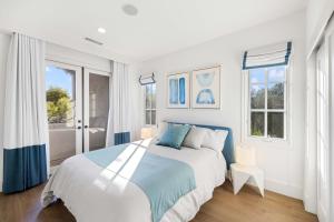 a white bedroom with a bed and two windows at @ Marbella Lane - 4BR Mediterranean-style Home in Newport Beach