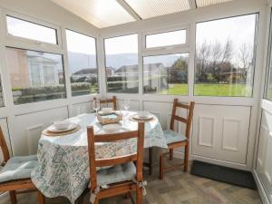 a dining room with a table and chairs and windows at Hafod-y-Gors in Fairbourne