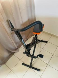 une chaise de bureau noire et orange assise devant un rideau dans l'établissement Prestige Spa Cayenne T2, à Cayenne
