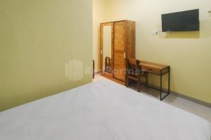 Dormitorio con cama, escritorio y TV en Asyura Kostel Syariah Redpartner, en Kedaton