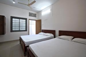 a bedroom with two beds and a window at Sarvam Lodge in Pīlamedu