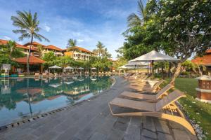 a row of lounge chairs next to a swimming pool at Ayodya Resort Bali in Nusa Dua