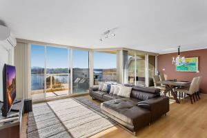 sala de estar con sofá de cuero y comedor en 2-Bed Unit with Balcony BBQ & Stunning Lake Views, en Belconnen