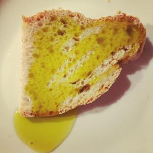 a piece of bread on a white plate with a green olive at Agriturismo Paradiso41 in Assisi