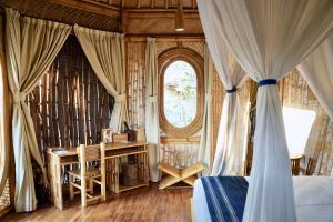 Waikelo的住宿－Maringi Sumba by Sumba Hospitality Foundation，一间卧室配有一张床、一张书桌和一个窗户。
