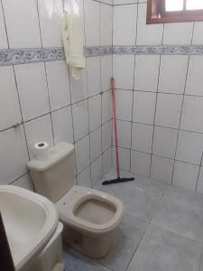 a bathroom with a toilet and a red mop at Casa espaçosa no Bethânia in Ipatinga