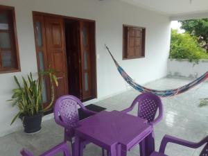 een paarse tafel en stoelen en een hangmat op een veranda bij Casa espaçosa no Bethânia in Ipatinga