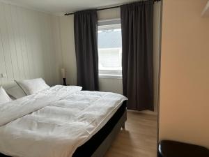 ein Schlafzimmer mit einem großen Bett und einem Fenster in der Unterkunft Sentral 4-roms leilighet i Trollbakken in Tromsø